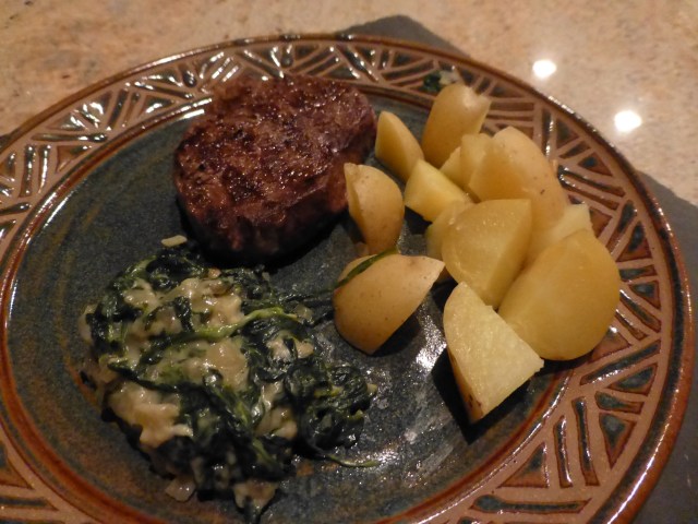 Grilled rib eye steak with steamed potatoes and creamed spinach