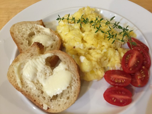 Scrambled eggs with fresh thyme, cherry tomatoes, and baguette 