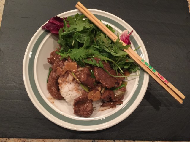 Mongolian beef served over rice with a green salad